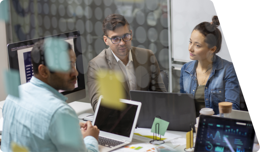 3 Personen sitzen nebeneinander am Bürotisch